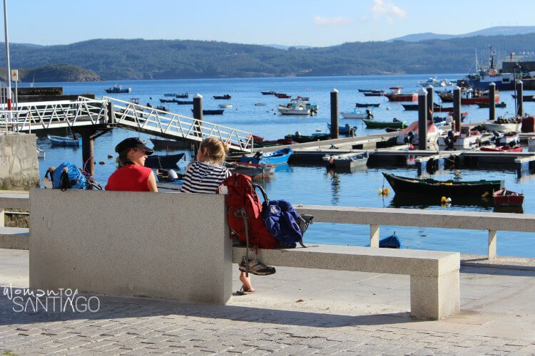 mujeres hablando en un banco frente al puerto